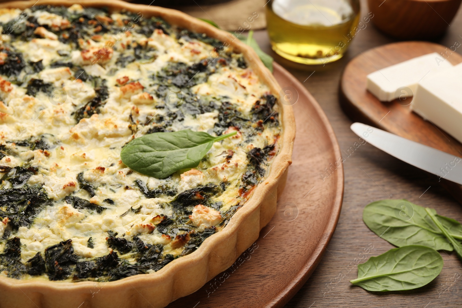 Photo of Delicious homemade spinach quiche on wooden board, closeup