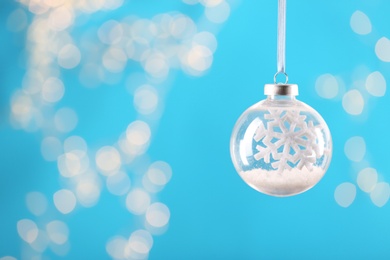 Photo of Decorative snow globe hanging on against blurred festive lights, space for text