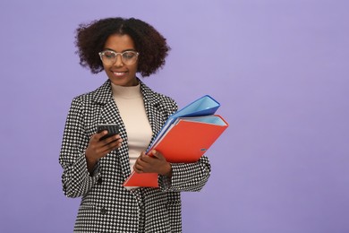 Photo of African American intern with folders using smartphone on purple background. Space for text