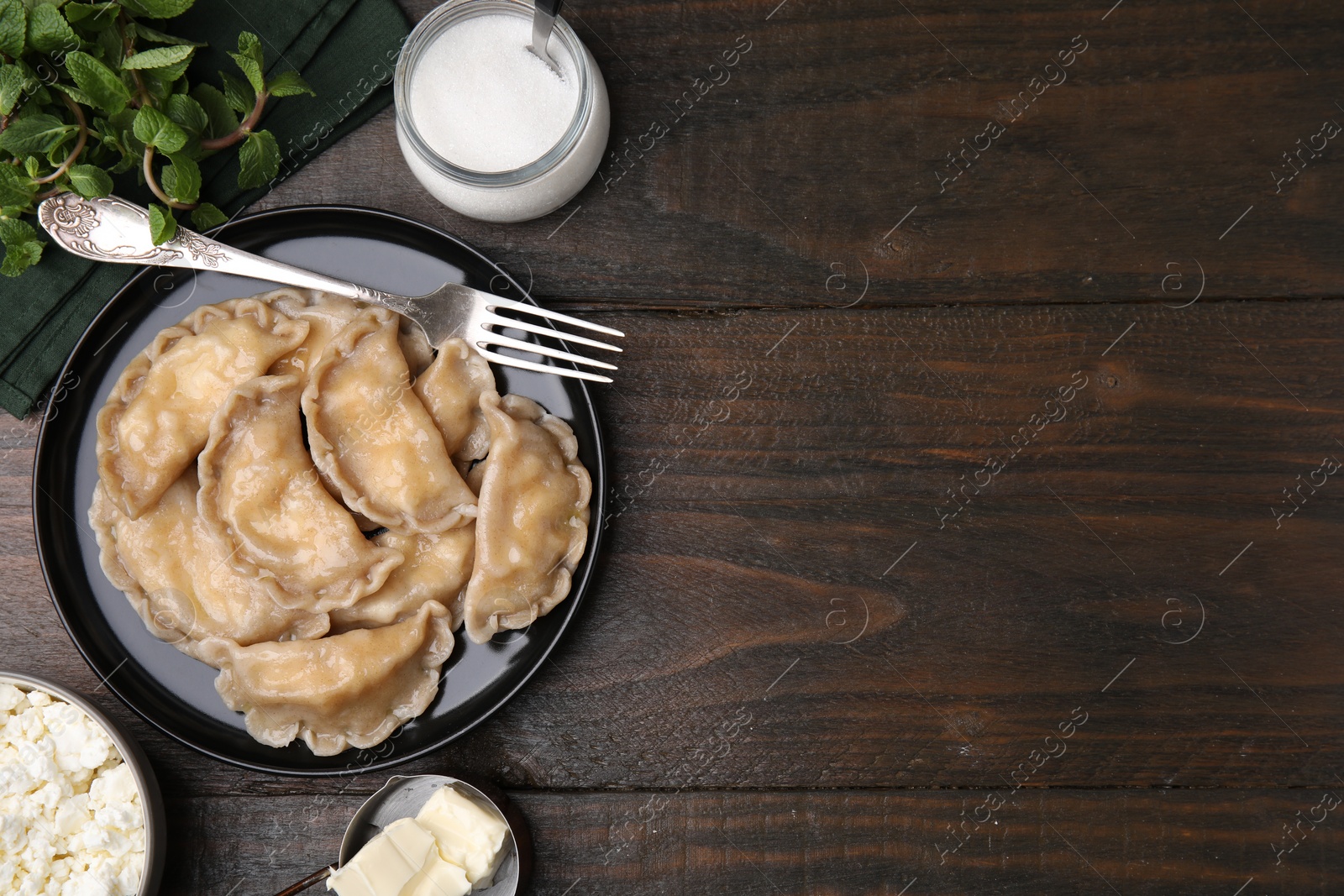 Photo of Delicious dumplings (varenyky) with cottage cheese served on wooden table, flat lay. Space for text