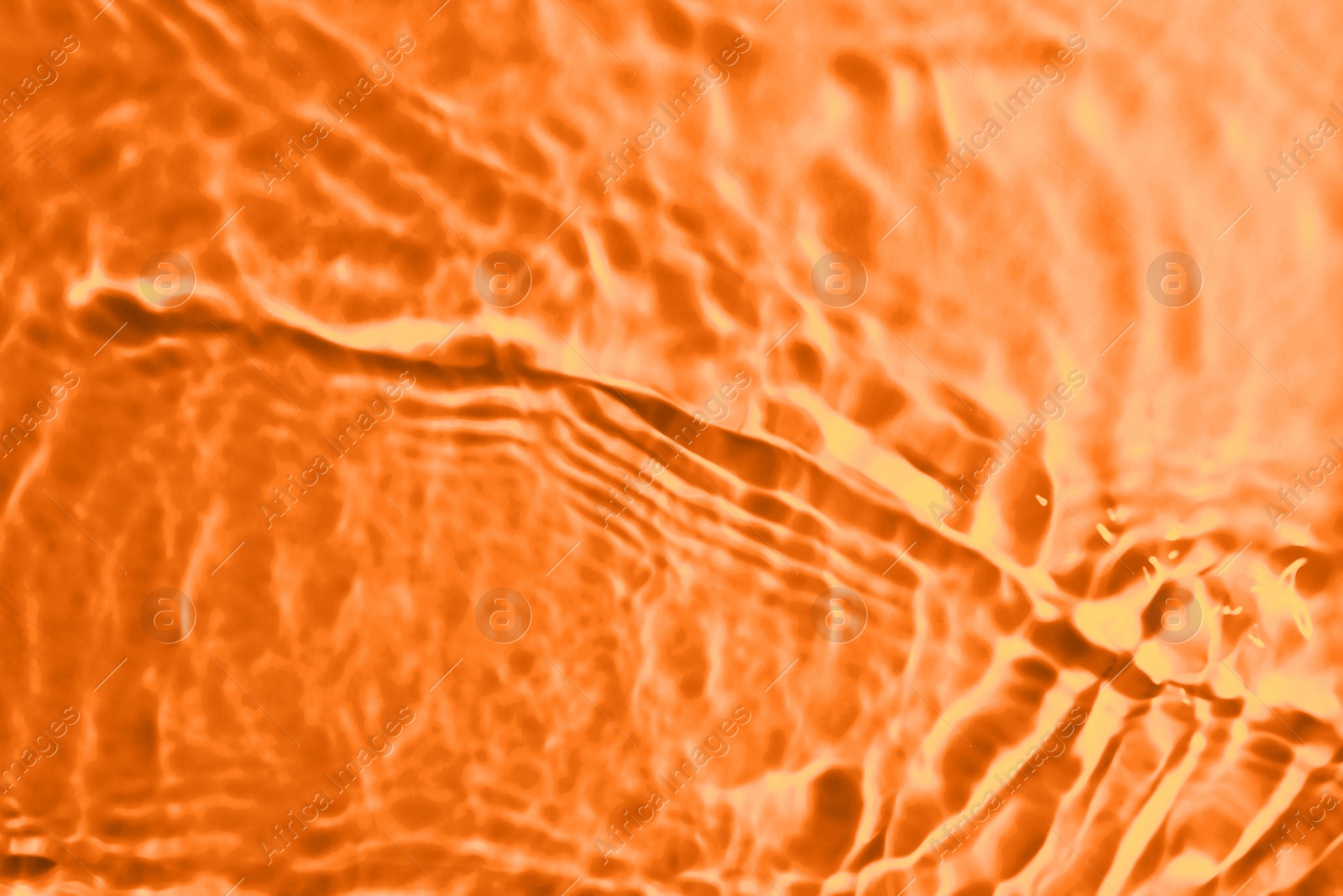 Image of Rippled surface of clear water on orange background