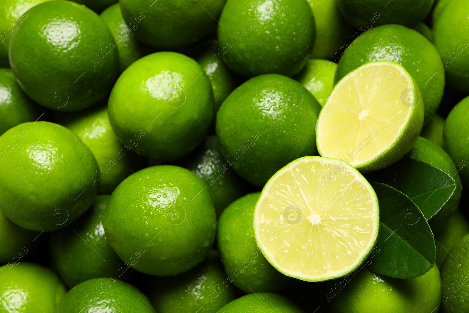 Photo of Fresh limes and leaves with water drops as background, top view
