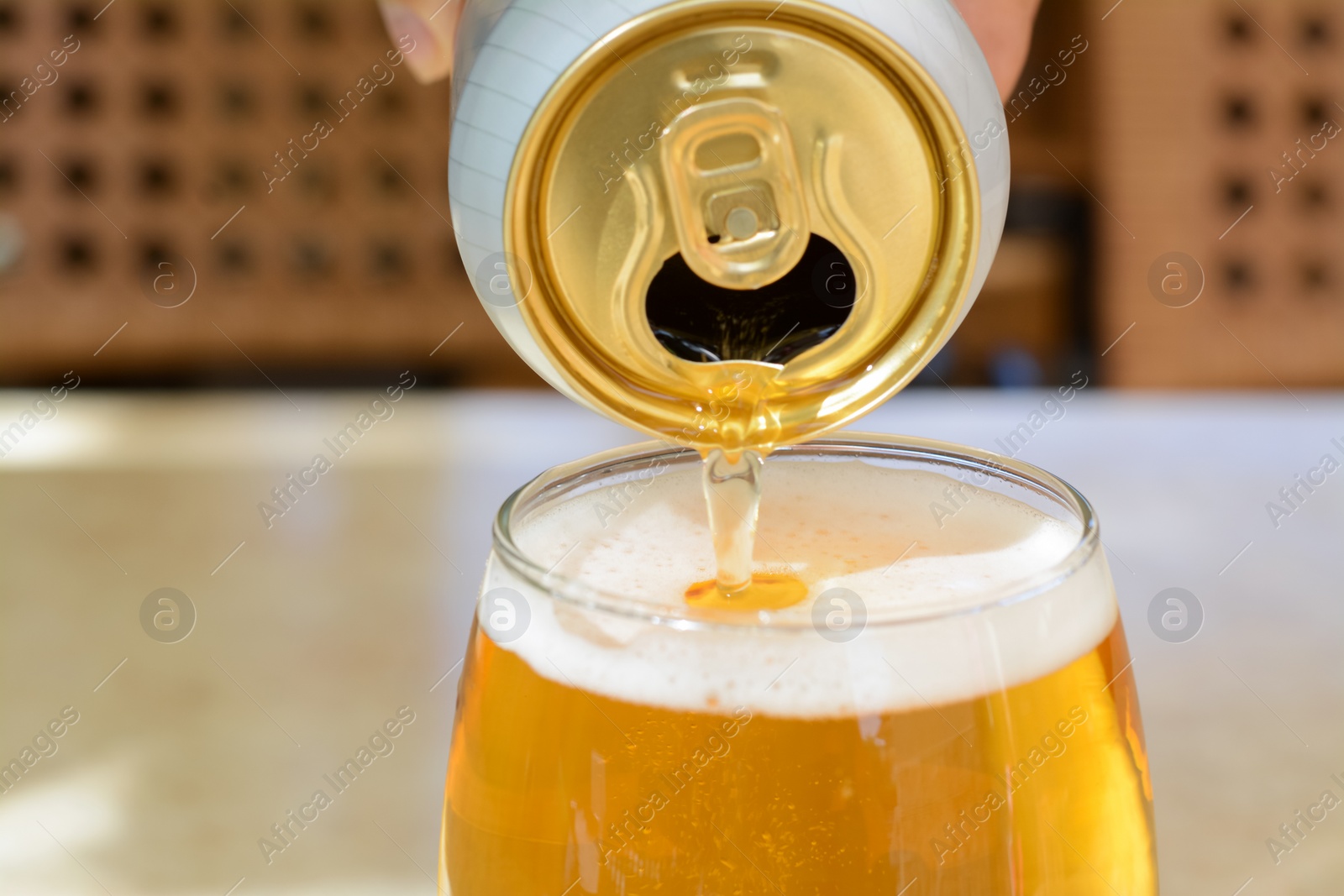 Photo of Pouring beer from can into glass on table, closeup