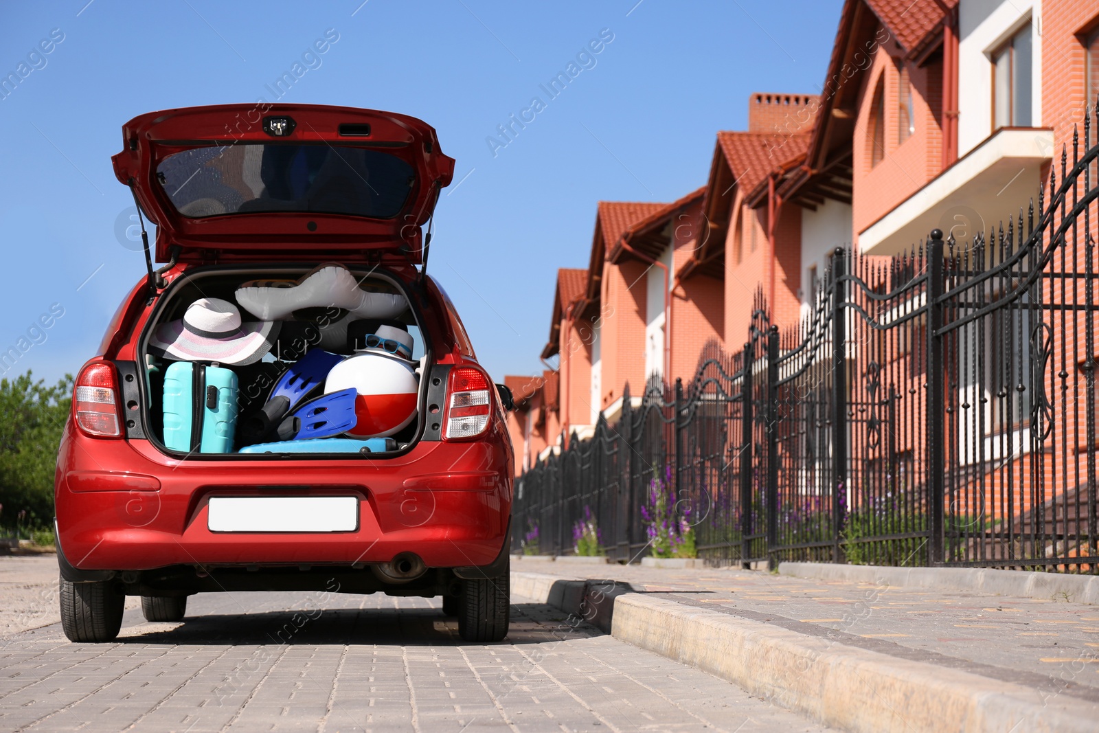 Photo of Family car with open trunk full of luggage in city. Space for text