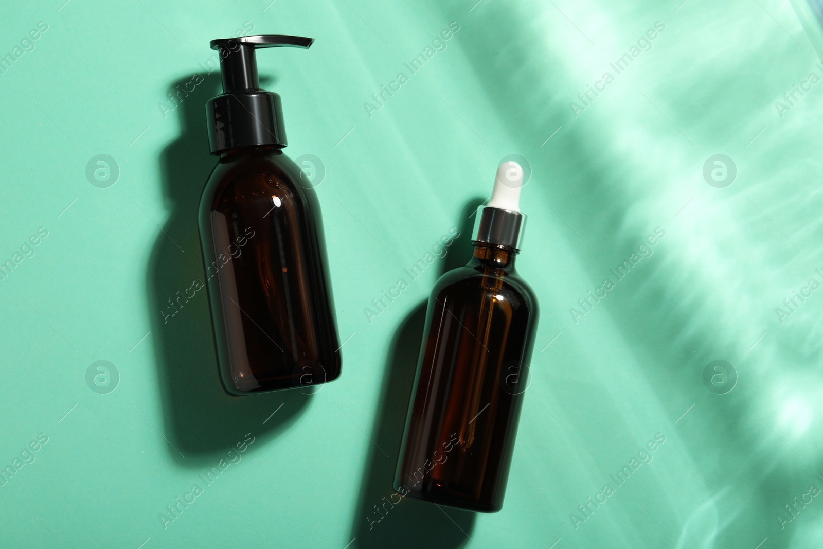 Photo of Bottles of hydrophilic oil on turquoise background, flat lay