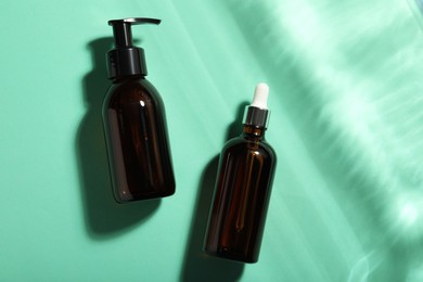 Bottles of hydrophilic oil on turquoise background, flat lay