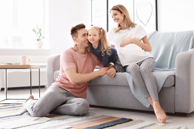 Young pregnant woman with her family at home