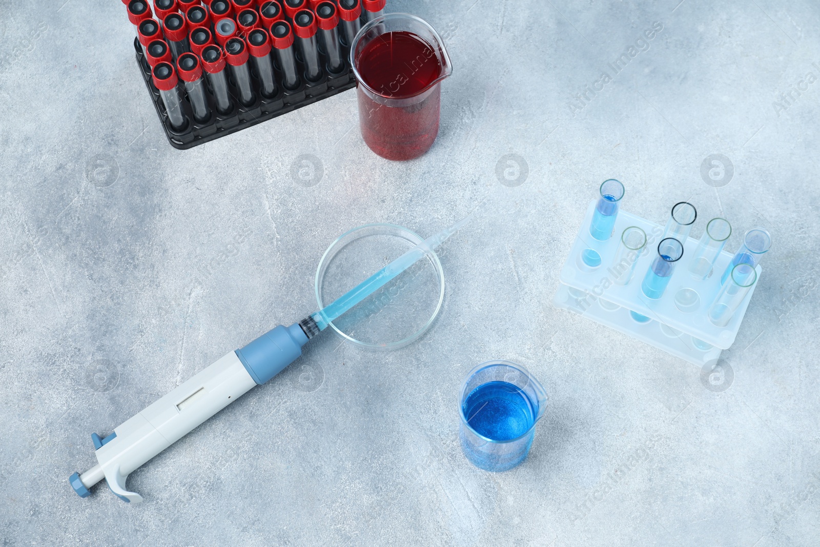 Photo of Laboratory analysis. Micropipette, petri dish, beakers and test tubes on light grey table, above view