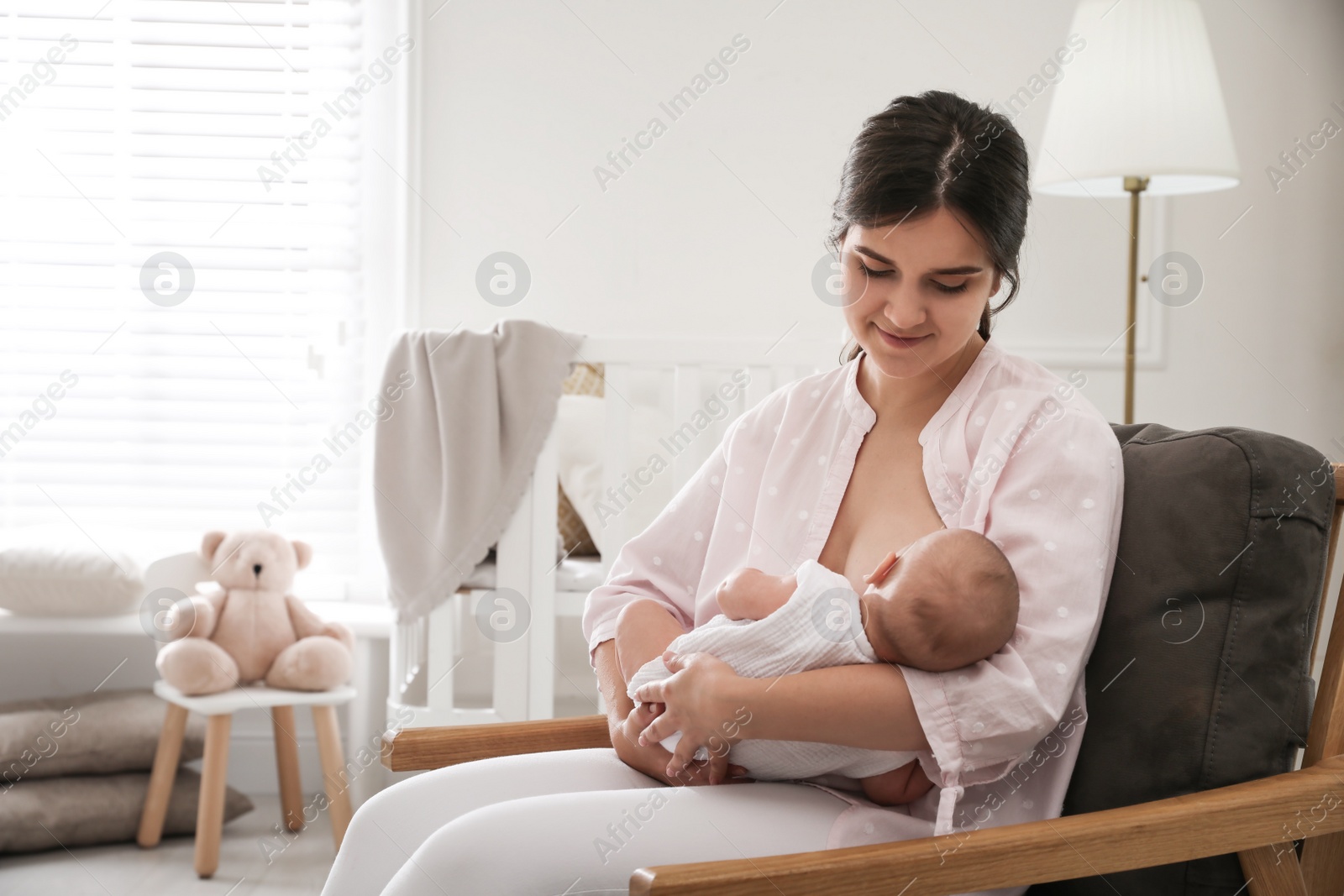 Photo of Young woman breastfeeding her little baby at home, space for text