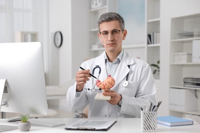 Photo of Gastroenterologist showing human stomach model at table in clinic