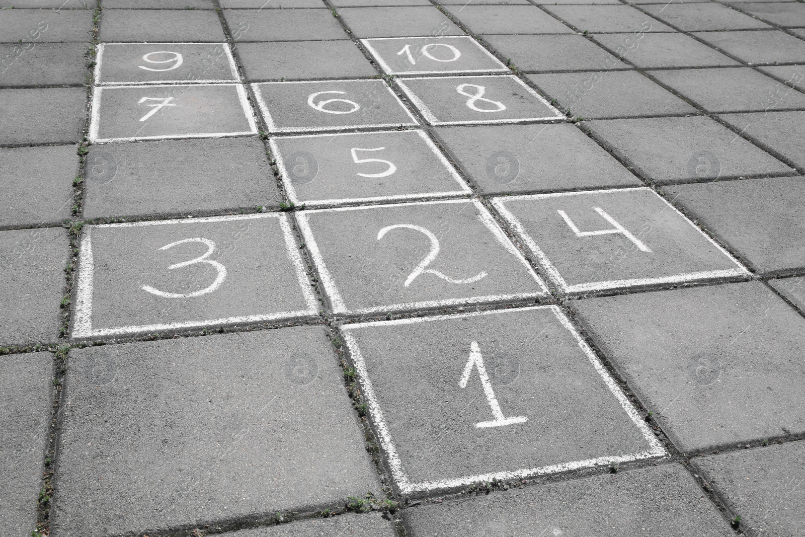 Photo of Hopscotch drawn with white chalk on street tiles outdoors