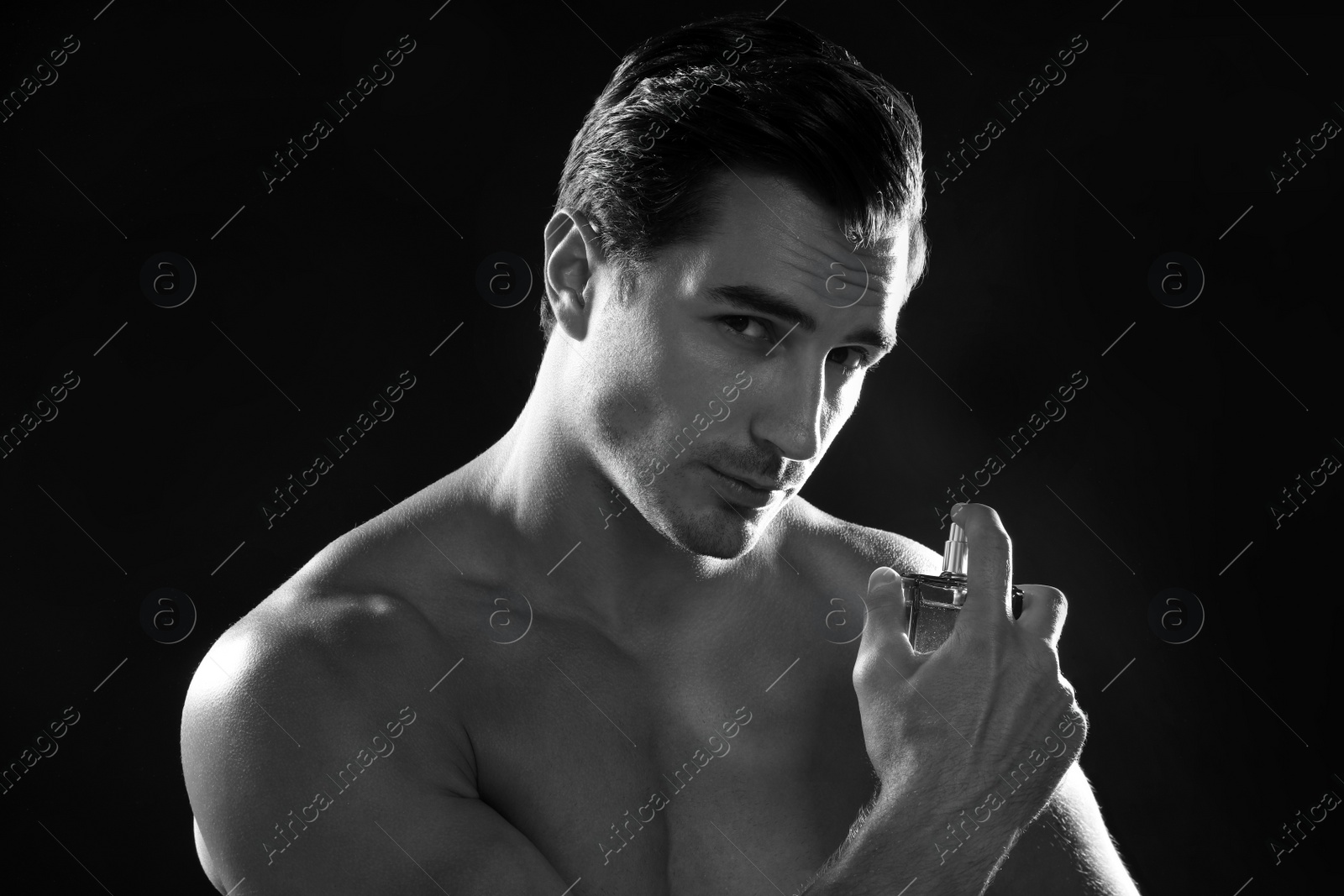 Photo of Handsome young man using perfume, black and white effect