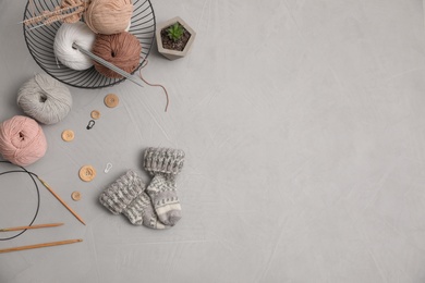 Photo of Flat lay composition with threads and knitted mittens on grey background, space for text. Engaging hobby