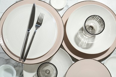 Photo of Stylish ceramic plates, cutlery and glasses on white marble table, flat lay