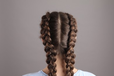 Woman with braided hair on grey background, back view