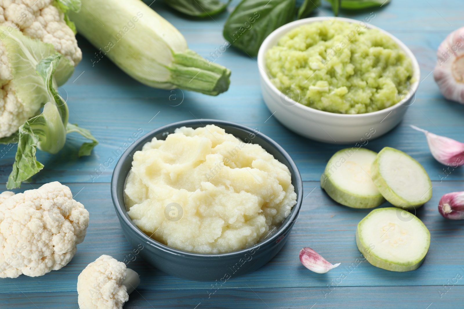 Photo of Tasty puree in bowls and ingredients on light blue wooden table