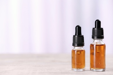 Bottles of essential oils on table against light background, space for text. Cosmetic products