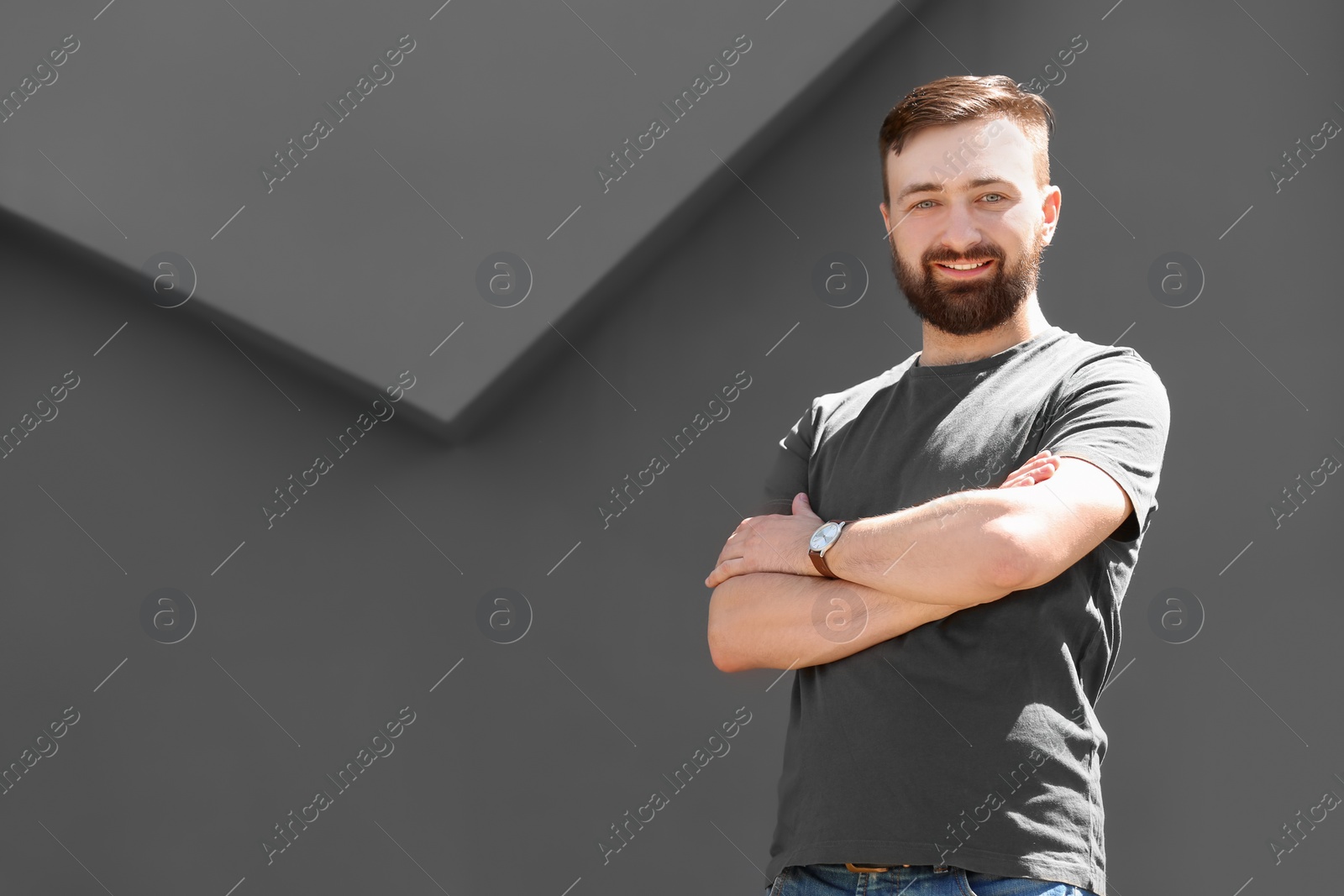 Photo of Portrait of young man in stylish outfit near grey wall