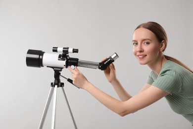 Happy astronomer with telescope on grey background