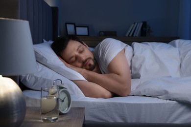 Photo of Handsome man sleeping in bed at night