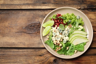 Photo of Fresh salad with pear on wooden table, top view. Space for text