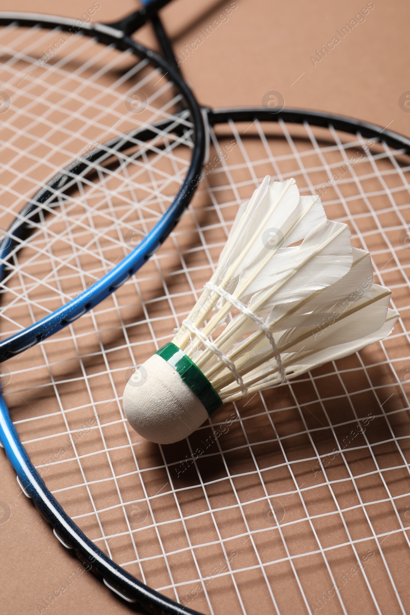 Photo of Feather badminton shuttlecock and rackets on brown background, closeup