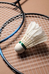Photo of Feather badminton shuttlecock and rackets on brown background, closeup