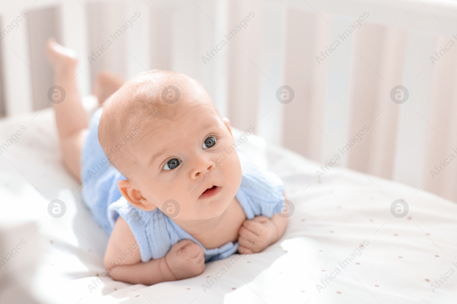 Photo of Cute little baby lying in crib at home, space for text