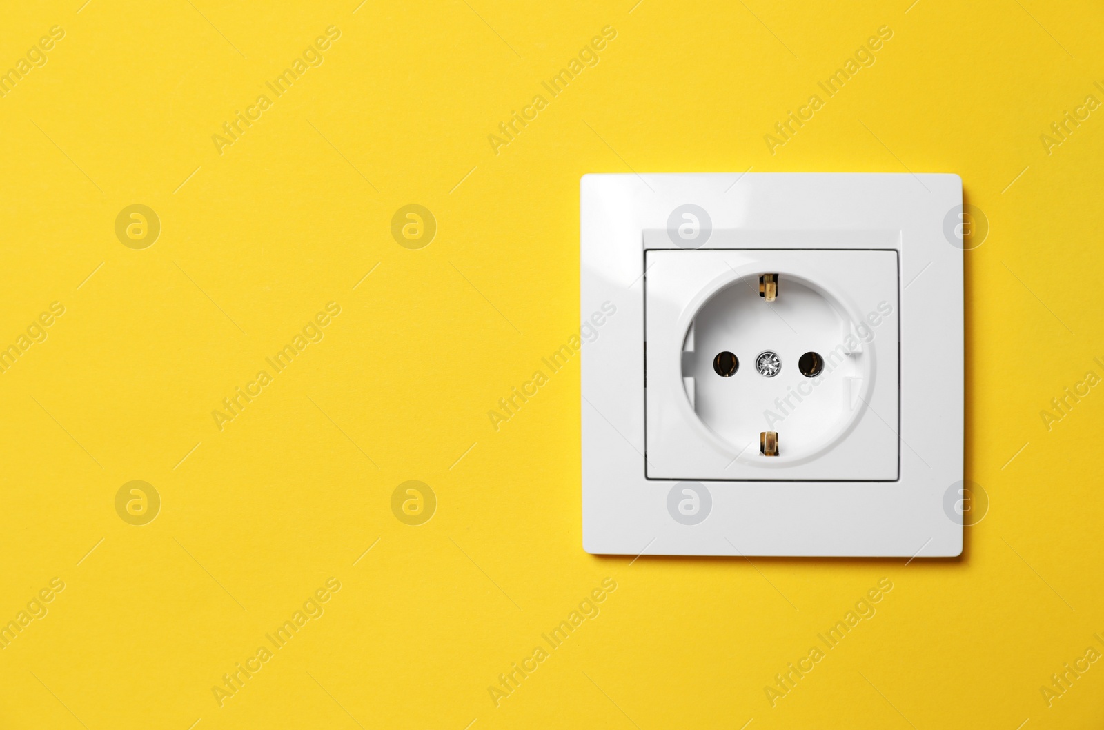 Photo of Power socket on yellow wall, space for text. Electrical supply