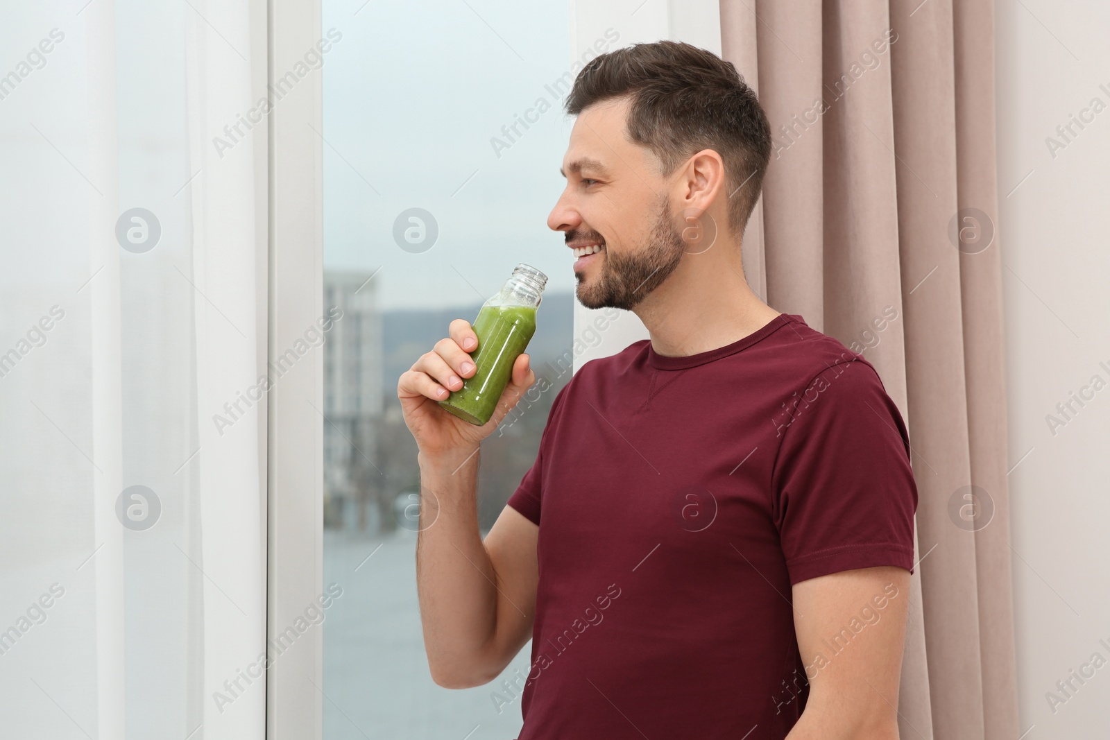 Photo of Man drinking delicious fresh smoothie indoors, space for text