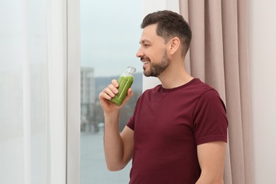 Photo of Man drinking delicious fresh smoothie indoors, space for text