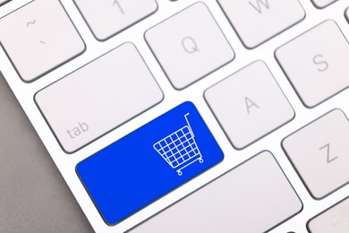 Image of Internet store. Blue button with shopping cart on computer keyboard, top view