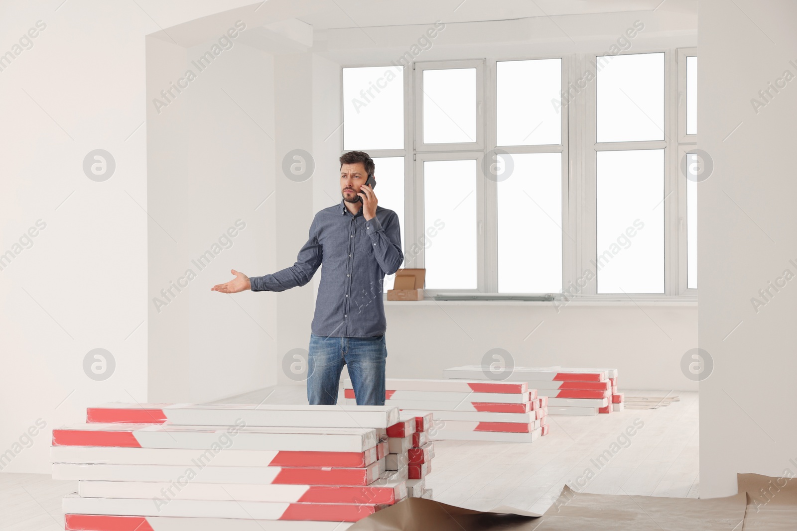 Photo of Man talking on phone in apartment during repair