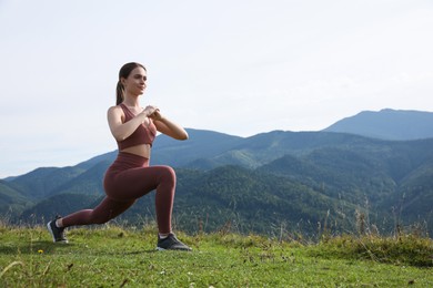 Young woman doing morning exercise in mountains, space for text