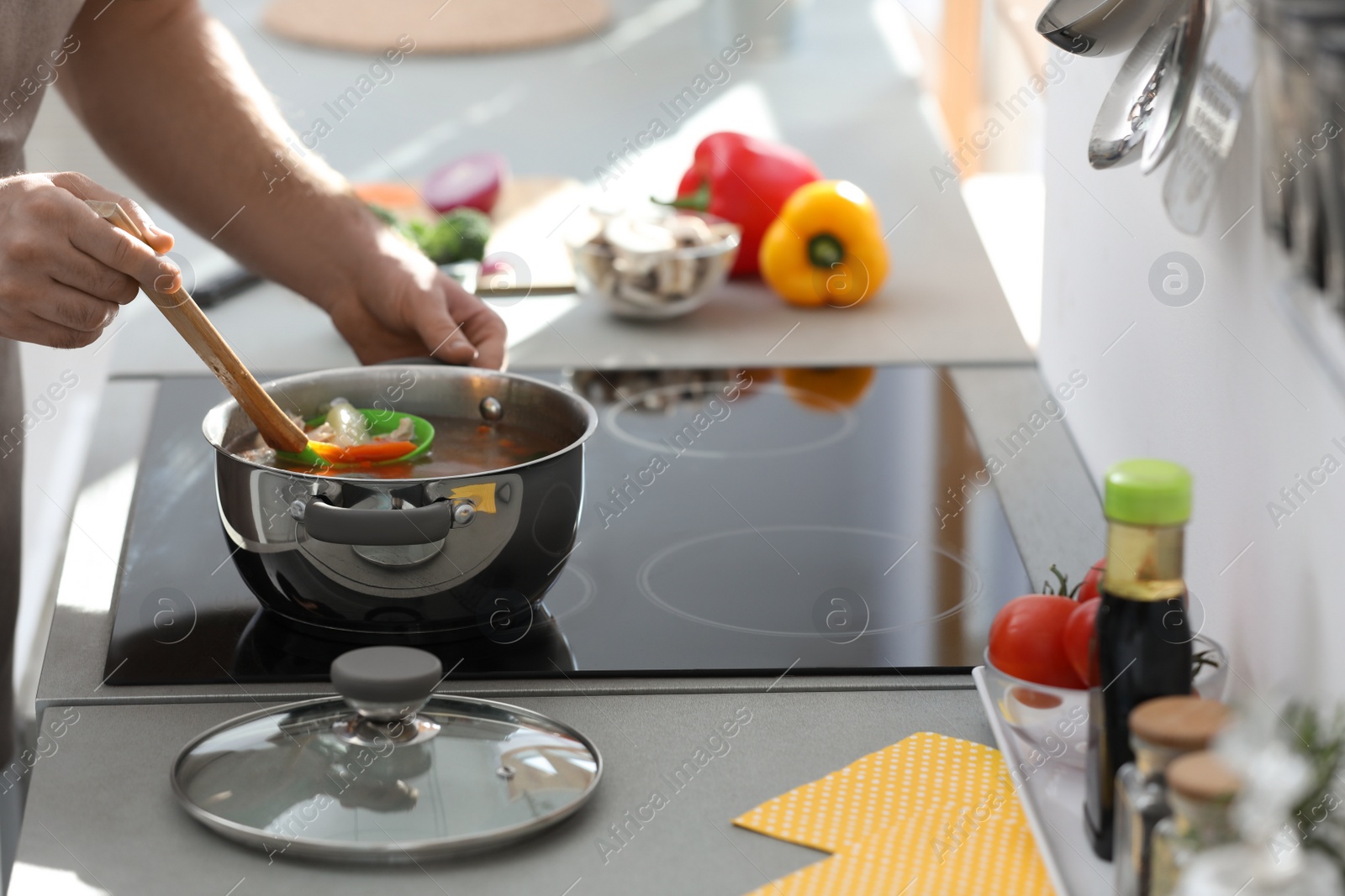 Photo of Young man cooking delicious soup in kitchen, closeup