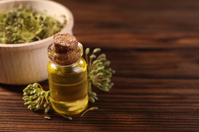 Photo of Bottle of essential oil and fresh dill on wooden table, closeup. Space for text