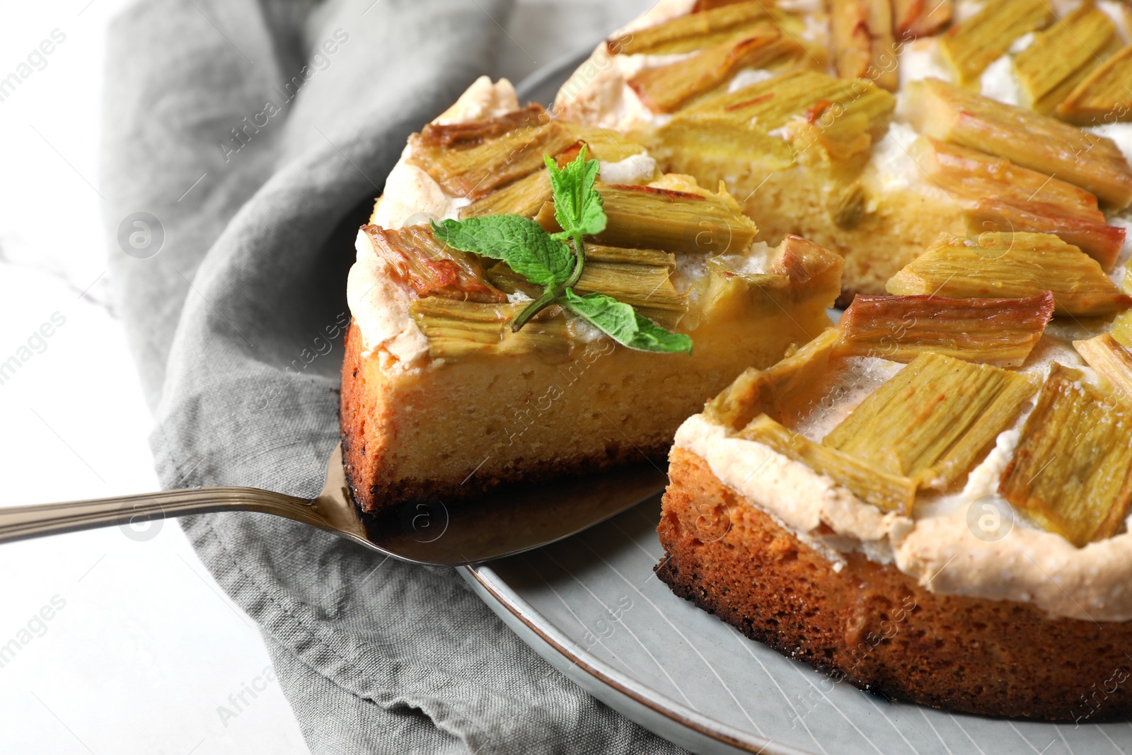 Photo of Freshly baked rhubarb pie and spatula on white table, closeup