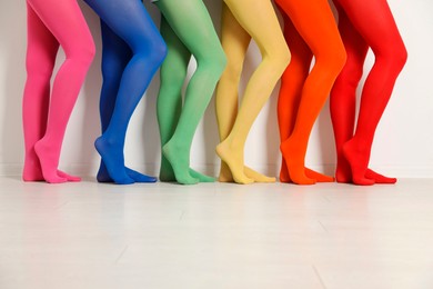 Photo of Women wearing colorful tights near white wall, closeup