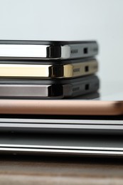 Stack of electronic devices on wooden table, closeup