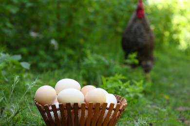 Photo of Fresh raw eggs in wooden bowl outdoors. Space for text