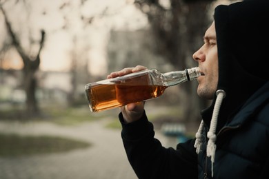 Photo of Addicted man drinking alcohol outdoors, closeup view