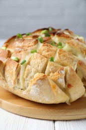Photo of Freshly baked bread with tofu cheese and green onions on white wooden table, closeup