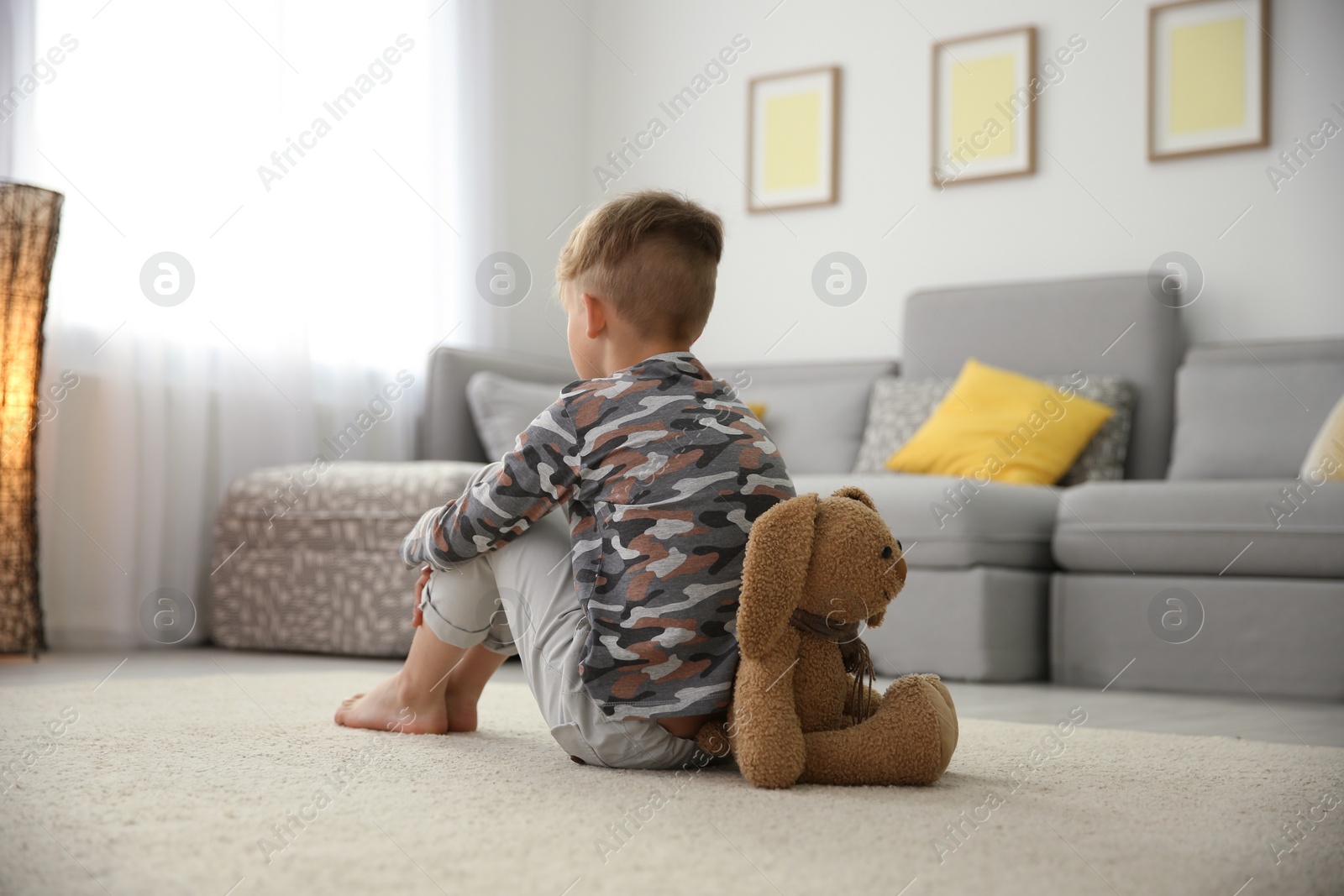 Photo of Little boy with toy sitting on floor in living room. Autism concept