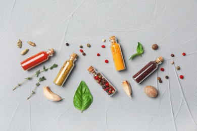 Glass bottles with different spices on gray background