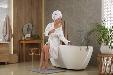 Beautiful woman sitting on edge of tub in bathroom