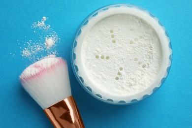 Photo of Rice loose face powder and makeup brush on light blue background, flat lay