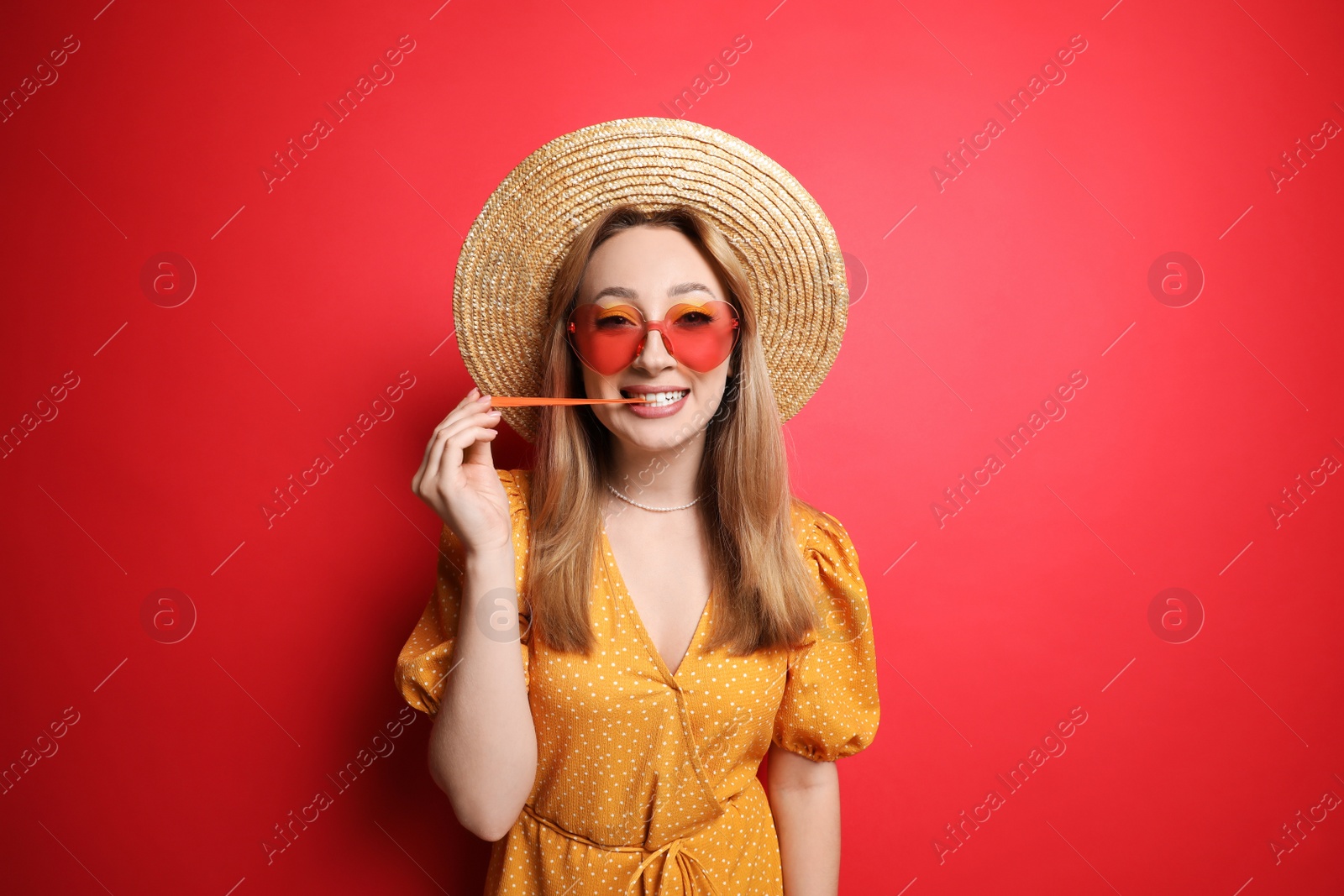 Photo of Fashionable young woman chewing bubblegum on red background