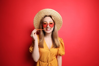 Fashionable young woman chewing bubblegum on red background