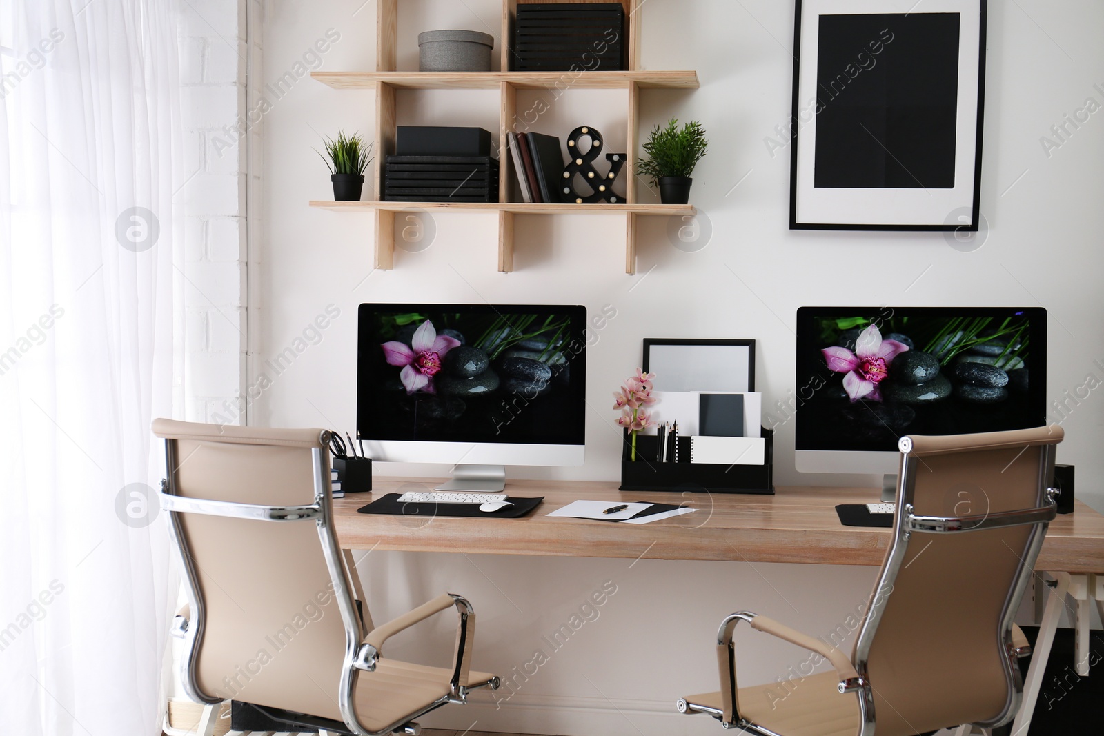 Photo of Modern workplace with large desk and computers in room. Stylish interior