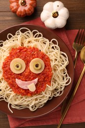 Plate with funny monster made of tasty pasta served on wooden table, flat lay. Halloween food